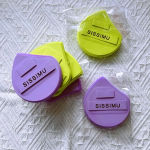 Macro detail of teardrop makeup sponges in purple and lime with branded ribbon straps