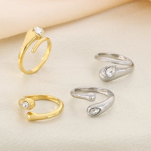 Detail of four gold and silver wrap rings featuring sparkling teardrop zircon stones