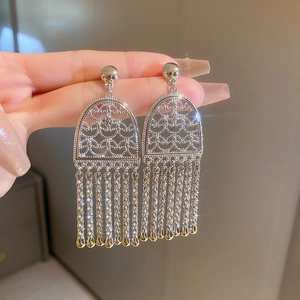 Close-up of sparkling zircon long tassel earrings with intricate hollow silver patterns