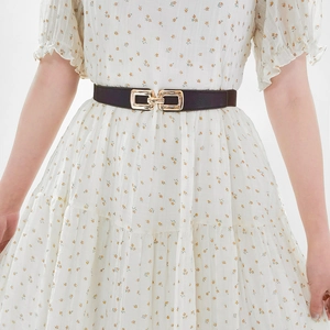 Detail of slim elastic waist belt with gold rectangular buckle on floral dress