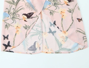 Gros plan détaillé de l'imprimé floral tropical rose avec oiseaux sur l'ourlet