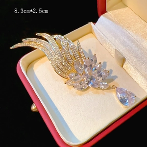 Detail view of gold phoenix brooch with zircon accents and water drop pearl pendant