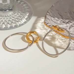 Close-up of assorted gold and silver stainless steel hoop earrings on glass