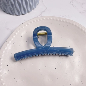 Close-up of deep blue glossy hair claw clip with a sleek twisted loop design and metal spring