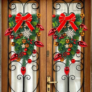 Christmas teardrop wreath with red bow and berries on a wooden glass door