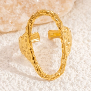 Irregular gold stainless steel open ring with textured surface on a stone base