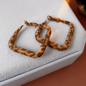 Détail de boucles d'oreilles carrées léopard avec flocage marron et tige en argent