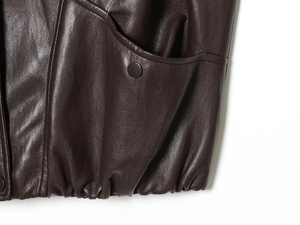 Close-up of brown PU leather vest pocket detailing with metal snap button and stitching