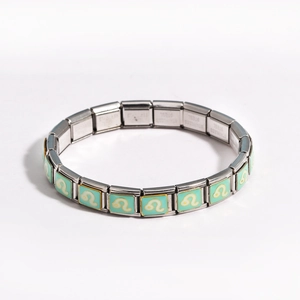 Detail of mint green enamel modular link charm with stainless steel floral scroll pattern
