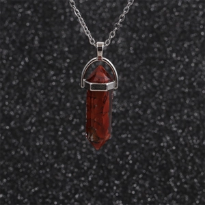 Detail of red hexagonal stone pendant in silver frame with textured background