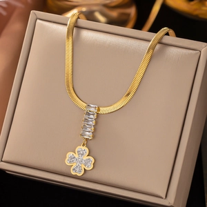 Close-up of golden snake chain necklace with rectangular zircons and clover pendant