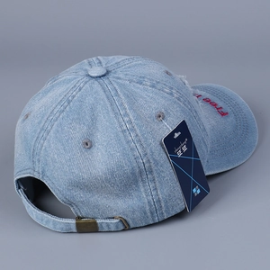 Detail of adjustable metal buckle and red embroidery on a light blue denim baseball cap