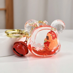 Detail of Capybara liquid oil keychain with strawberry bear inside and red bell accessory