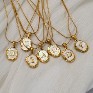 Collier lettre en acier titane plaqué or 18K avec nacre et contour texture lave