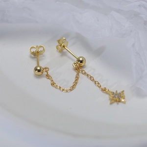 Detailed macro view of gold chain earrings featuring sparkling star charms and polished beads