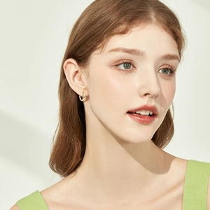 Elegant gold U-shaped moissanite leaf hoop earrings worn by a model in soft light