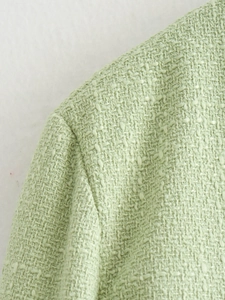 Close-up of light green tweed jacket shoulder showing textured woven fabric details