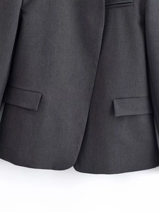 Détail de la veste de tailleur gris foncé avec poches à rabat et ourlet arrondi