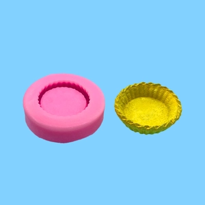 Detailed pink silicone tart shell mold next to a golden baked crust product