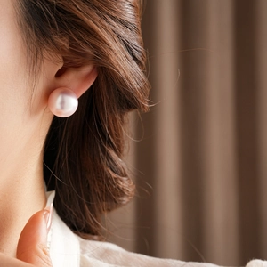 Close-up of a pink-purple pearl earring on a woman's ear with high-end texture