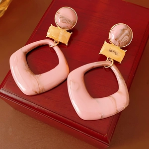 Detail of pink marble resin geometric earrings with gold links on a vintage wood box