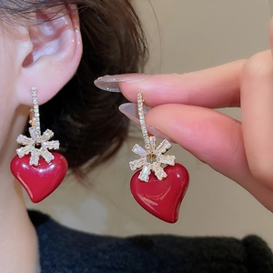Macro shot of red heart stud earrings with gold snowflake zircon inlay for women