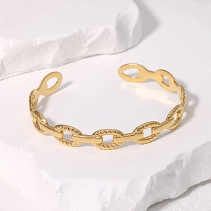 Macro detail of gold geometric chain link texture on stainless steel open cuff bracelet
