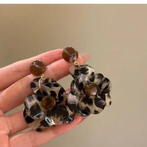 Detail of leopard print resin flower earrings with gold ring and brown center