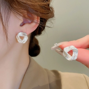 Minimalist silver triangle earrings with textured sandy finish shown on a model's ear