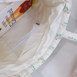 Vue intérieure du sac cabas matelassé à fleurs avec une poche zippée blanche pratique