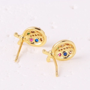 Golden ladybug stud earrings with colorful zircon stones on white textured surface
