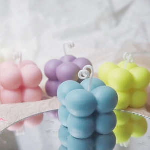 Bubble cube aromatherapy candles in pink, purple, blue, and yellow with mirror reflection