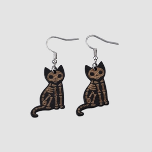 Macro detail of gothic black wooden earrings with golden cat skeleton bone patterns