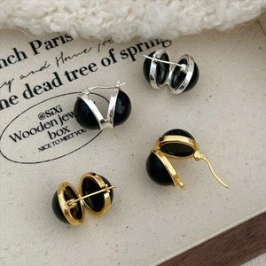 Close-up of black onyx drop earrings in silver and gold minimalist metal frames