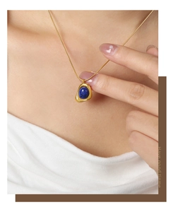 Detail view of gold snake chain with geometric pendant featuring deep blue natural stone