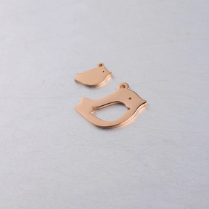 Detail view of rose gold hollow and solid bird charms on a textured background