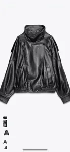 Close-up of black oversized biker jacket showing grainy leather texture and elastic hem