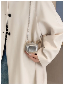 Close-up of a mini silver metallic suitcase-style crossbody bag with chain strap