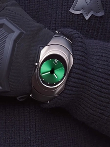 Close-up of a Y2K irregular men's watch with a green dial worn over a black glove