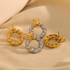 Détail de boucles d'oreilles torsadées en or avec nœud croisé sur un fond de tissu élégant