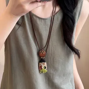 Collier ethnique avec perles en céramique, disque en bois et pompon vert sur lin