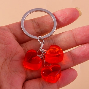 Detail view of three red transparent heart charms on a silver keychain held in hand
