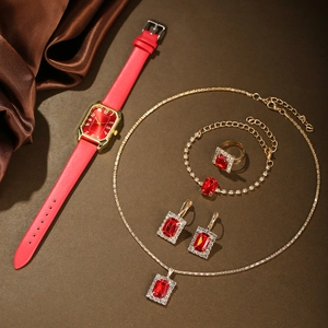 Detailed set of gold watch and jewelry with red stones and diamonds on brown silk
