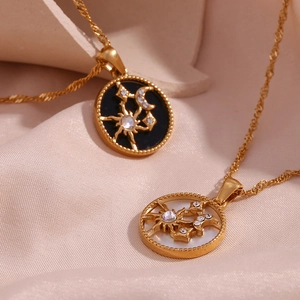 Detail of gold sun and moon pendants with rhinestones on soft pink silk background
