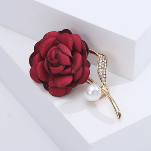 Detail of elegant dark red fabric rose brooch with gold leaves, pearls and rhinestones