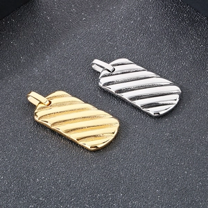 Detail of gold and silver rectangular bar pendants with industrial diagonal textured grooves