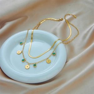 Double-layered gold snake chain necklace with turquoise floral pendants in ceramic tray