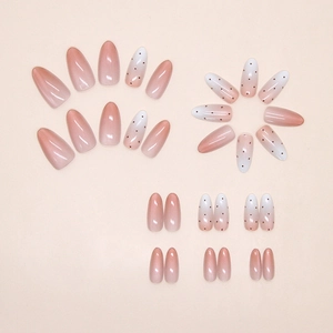 Detail of almond press-on nails featuring red-brown gradient and minimalist polka dot design