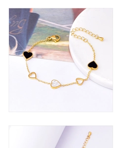 Detail of gold heart bracelet with black enamel, white mother of pearl and hollow charms