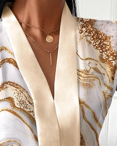 Detail of layered gold necklaces with textured coin and bar charms on model